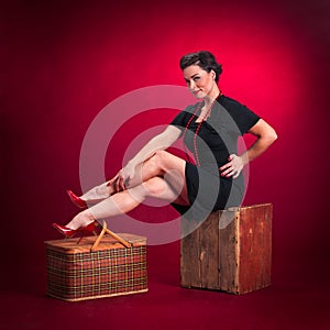 Pinup Girl in Black Dress Sits on Wooden Box