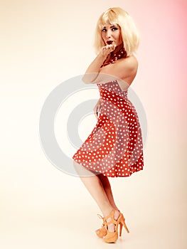 Pinup girl in blond wig retro dress blowing a kiss