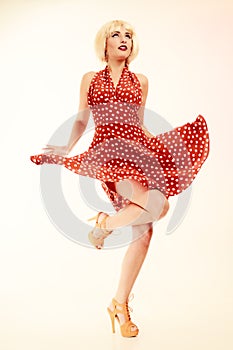 Pinup girl in blond wig retro dress dancing