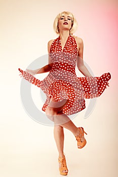 Pinup girl in blond wig retro dress dancing