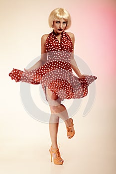 Pinup girl in blond wig retro dress dancing