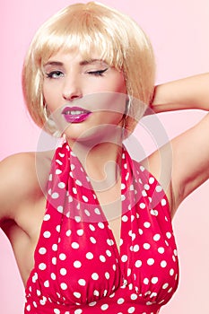 Pinup girl in blond wig and retro red dress winking. Vintage.