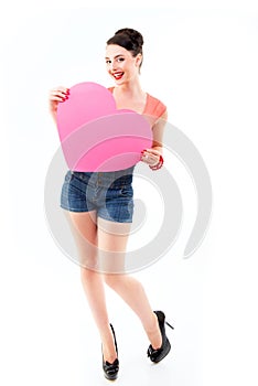 Pinup girl holding pink heart and happy smiling, full length. Retro portrait of young cheerful woman in pin-up style