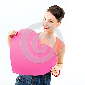 Pinup girl holding pink heart and happy smiling. Retro portrait of young cheerful woman in pin-up style