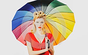 Pinup girl with rainbow umbrella at rain weather. Rainy autumn mood, pin up woman red dress isolated white.