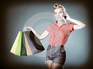 Pinup girl with shopping bags calling on the phone