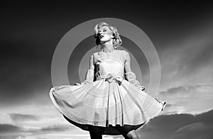 Pinup style woman in summer dress on dramatic sky. Fashionable young model in style dress. Fashion woman in summer.