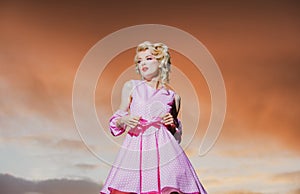 Pinup style woman in summer dress on dramatic sky. Stylish fashion woman posing outdoor. Attractive young woman in sexy