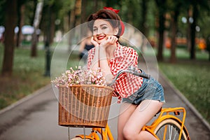 Pinup woman on bicycle with backet of flowers photo