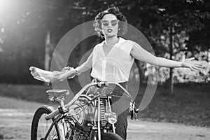 A pinup woman in a vintage dress posed next to the old motorcycle