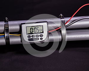 Pipe bomb with an clock timer to trigger detonation on black background