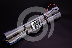 Pipe bomb with an clock timer to trigger detonation on black background