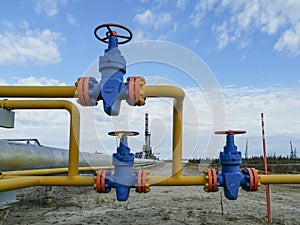 Pipe fittings of gas wells against the background of a drilling rig.