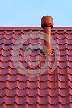 Pipe of a modern ventilation system on the roof of the house with metal tiles
