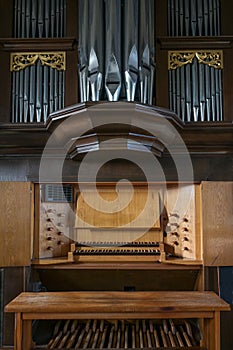 Pipe organ console with two keyboards or manuals, stop knobs, pedal board, and case facade in the St. Mary`s Church of Gudow,