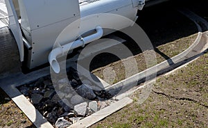 a pipe in the shape of a car exhaust is bent into a drainage pit filled with