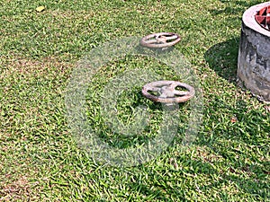 Pipe water valve and well on green grass background near by waste water treatment system.