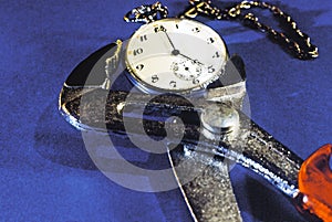 A pipe wrench gripping a vintage pocket watch. Conceptual.