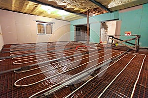 Pipefitter installing system of heating or underfloor heating installation. Water floor heating system interior