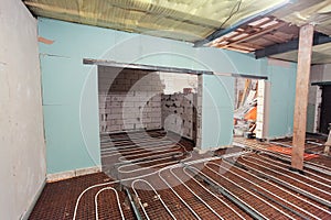 Pipefitter installing system of heating or underfloor heating installation. Water floor heating system interior
