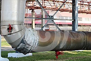 Pipeline estocad, large steam pipe in insulation made of fiberglass with red ventrals, fittings, valves, drainage with blue beams