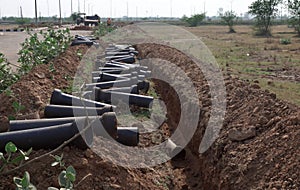 Pipeline tubes laying on side of a digging drain, construction work of pipeline on progress.