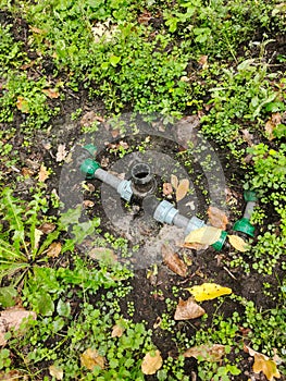 Pipes and fittings of part of the drip irrigation system in the grass in the garden area