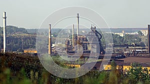 Pipes of industrial plant smoke among green trees and nature in Alapaevsk.