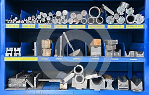 pipes, metal pieces and various metal parts for a CNC machine standing on a shelf