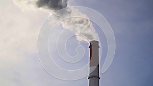 Pipes with smoke: industrial production, plant, air pollution. Dense thick smoke comes from industrial red-white pipes
