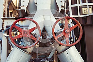 Pipes and valves with red knobs on industrial plant