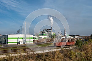 Pipes of woodworking enterprise plant sawmill near river. Air pollution concept. Industrial landscape environmental pollution