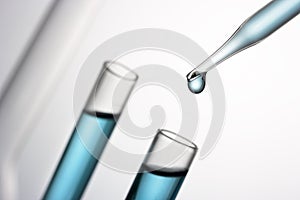 Pipette adding blue fluid in test tube close up.