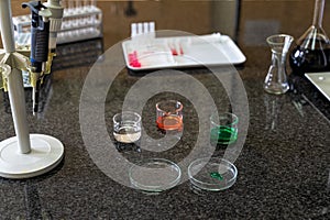 Pipette and colourful chemical liquid solutions in flasks on laboratory worktop