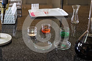 Pipette and colourful chemical liquid solutions in flasks on laboratory worktop