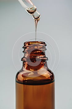 Pipette with cosmetic oil over a brown bottle