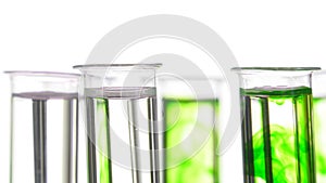 Pipette depositing drops of green dye in rotating test tubes