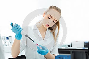 Pipette dropping a sample in a test tube. Laboratory assistant analyzing blood in lab. DNA analysis