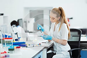 Pipette dropping a sample in a test tube. Laboratory assistant analyzing blood in lab. DNA analysis