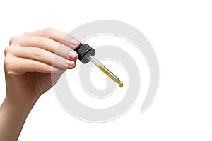 A pipette with essential oil in woman's hand isolated on white background. Droplet of essential oil on white background