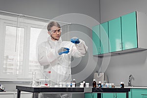 Pipette in hand. Technician in blue gloves pouring something into the test tube and looking busy