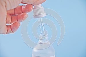 Pipette with liquid. A drop of dripping in a clear bottle. Female hand holding a dropper with liquid