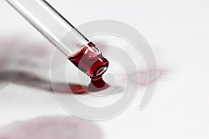 pipette with wine drops on white sheet with stains