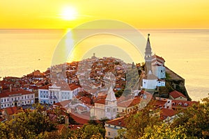 Piran Old Town, Slovenia, scenic cityscape with medieval architecture, church, sea and sky at sunset, outdoor travel background