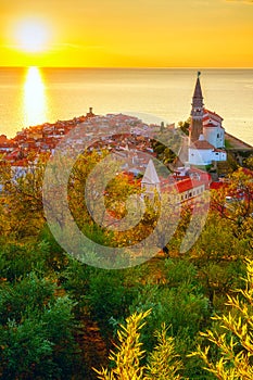 Piran Old Town, Slovenia, scenic cityscape with medieval architecture, church, sea and sky at sunset, outdoor travel background