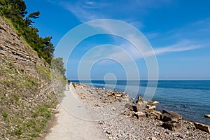 Piran - Tourist woman on scenic walking path between Fiesa and charming coastal town of Piran