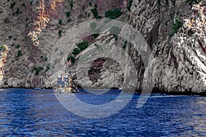 Pirate schooner in the blue sea against the backdrop of a rocky cliff