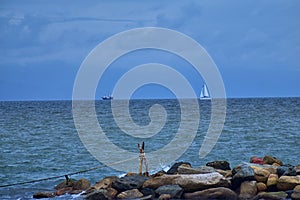 Pirate Ship and Sail Boat off in the distance with rocks in foreground from beach in Puerto Vallarta Mexico.