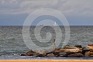 Pirate Ship and Sail Boat off in the distance with rocks in foreground from beach in Puerto Vallarta Mexico.