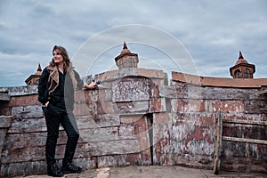 A pirate woman stands with a knife at the wooden side of an old sailing ship